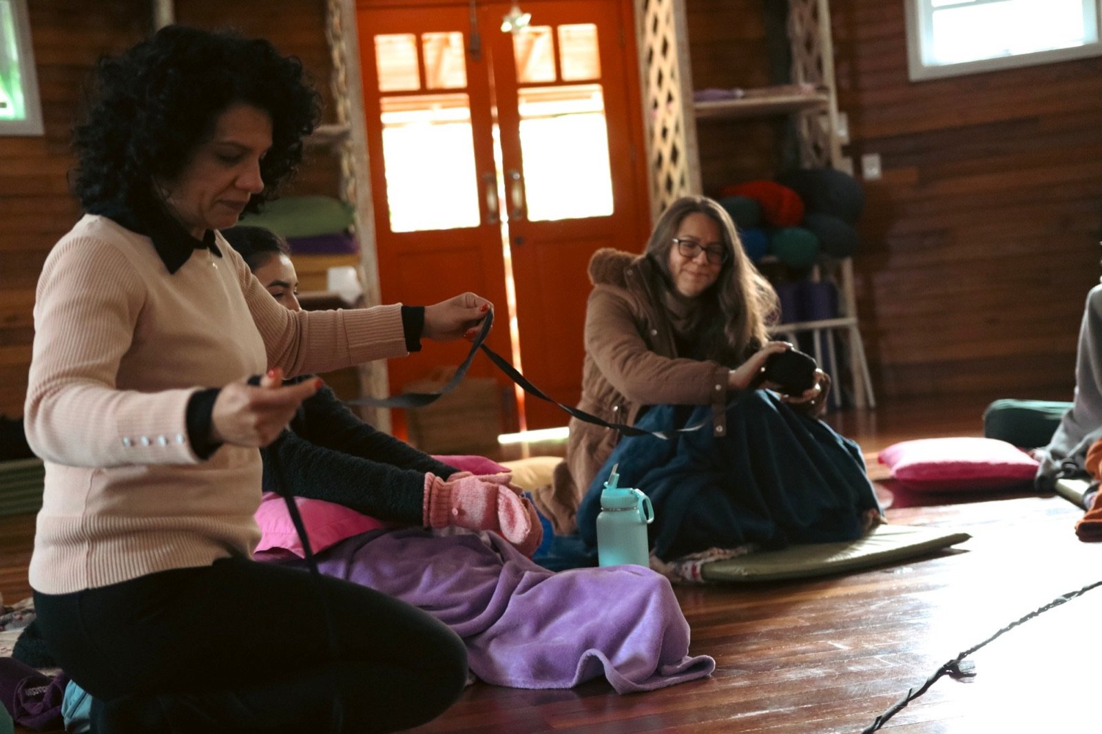 Participantes sentadas no chão da Casa Curadores desenrolando um fio